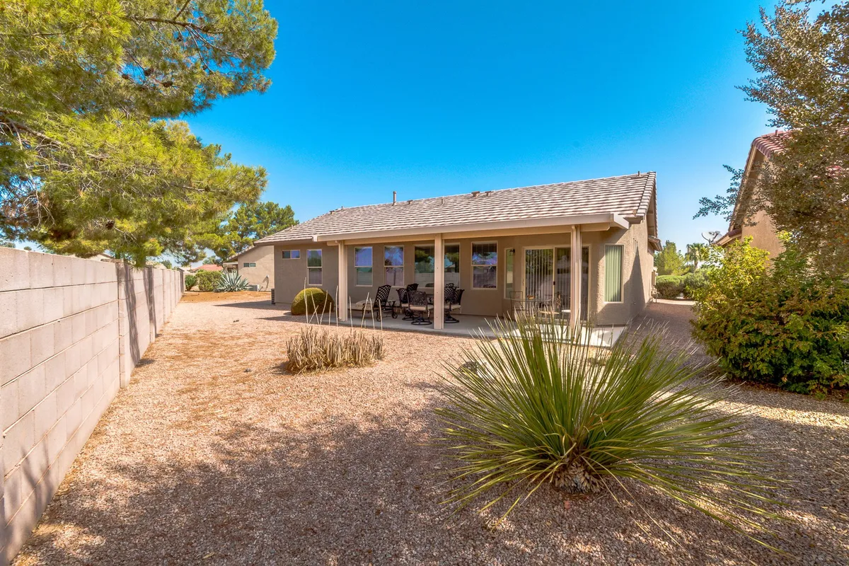 A back patio scene with desert landscaping and a comfortable seating area. The setting is tranquil, ideal for relaxing outdoors after a day of shopping or sightseeing. Sunsets and morning light create a serene atmosphere.