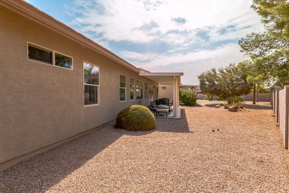 Outdoor seating nestled alongside a gravel pathway and green shrubbery, perfect for enjoying quiet mornings or casual gatherings. The space feels intimate and peaceful, surrounded by natural elements.