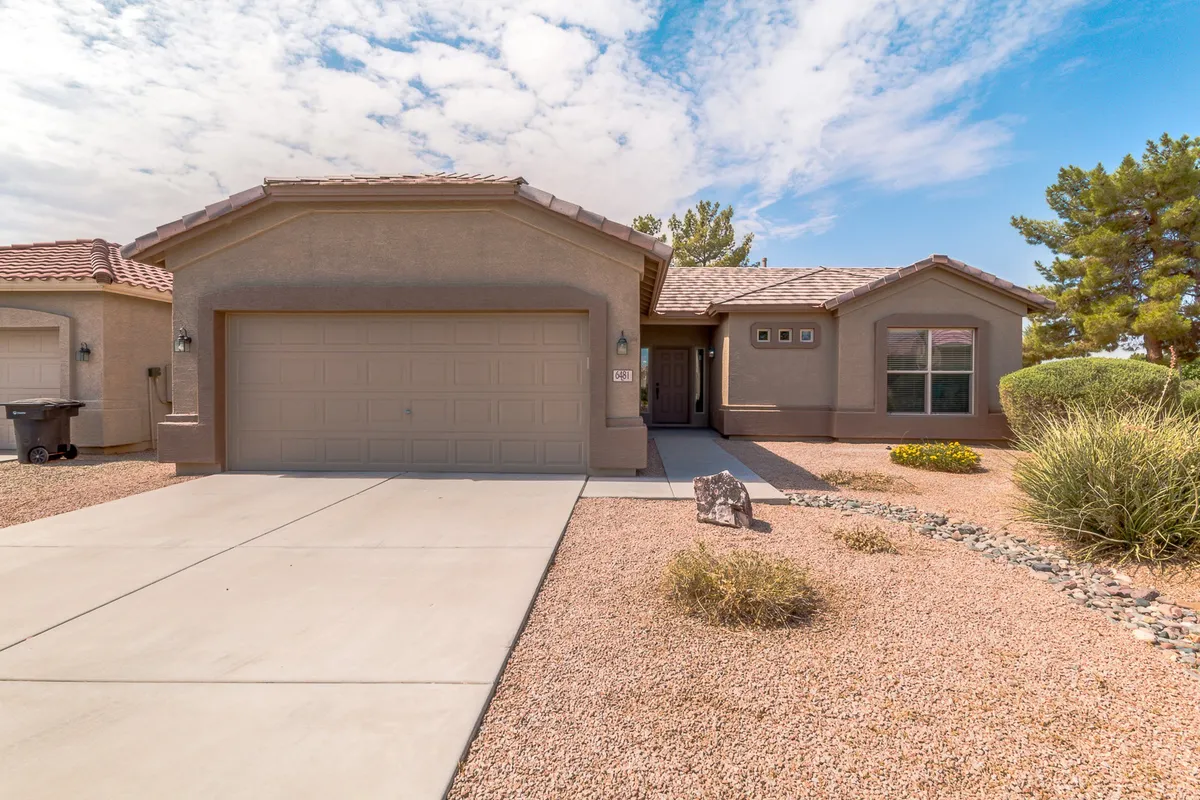 This image captures the front of the property, featuring a welcoming front door and a well-landscaped yard. The garage door is also visible, and the tidy front space suggests a serene, well-maintained community setting.