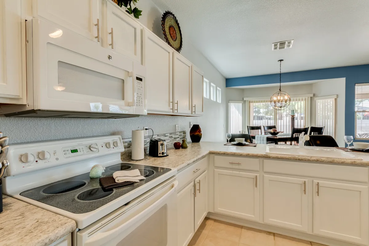 A modern kitchen with stainless steel appliances, a granite countertop, and a glimpse of the dining area in the background. The space is clean, updated, and ready for immediate use, reflecting both style and functionality.