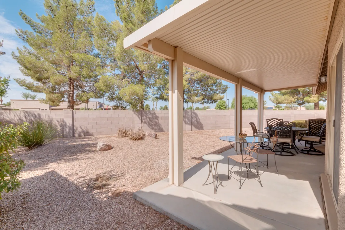 The photo features an outdoor dining area with a table and chairs set amidst a tranquil gravel yard and lush greenery. The space is ideal for sunset views, social gatherings, and alfresco meals, encouraging outdoor activity and neighborly interaction.