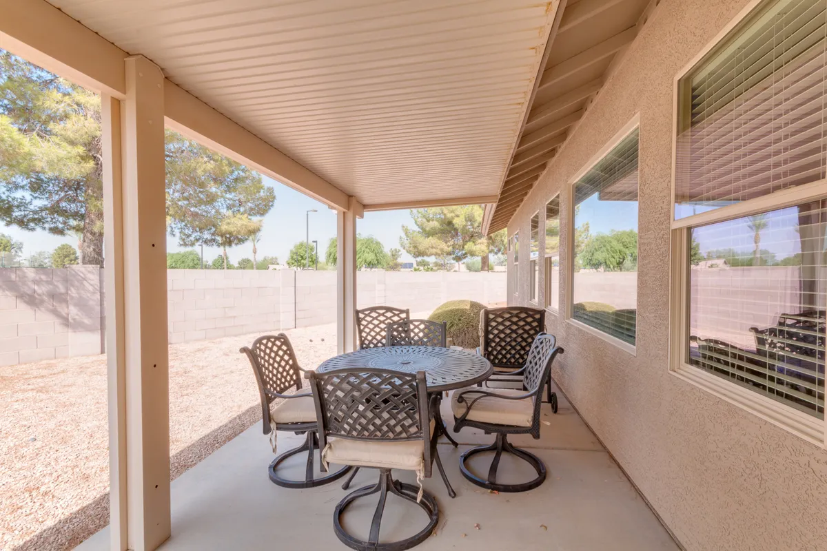 An inviting covered patio with a spacious outdoor dining table surrounded by six chairs, nestled beneath a sturdy patio cover. The patio is bordered by lush greenery and decorative landscaping, offering ample space for outdoor gatherings, meals, and relaxation. The space is bathed in natural light, highlighting the effortless connection between indoor comfort and outdoor enjoyment.